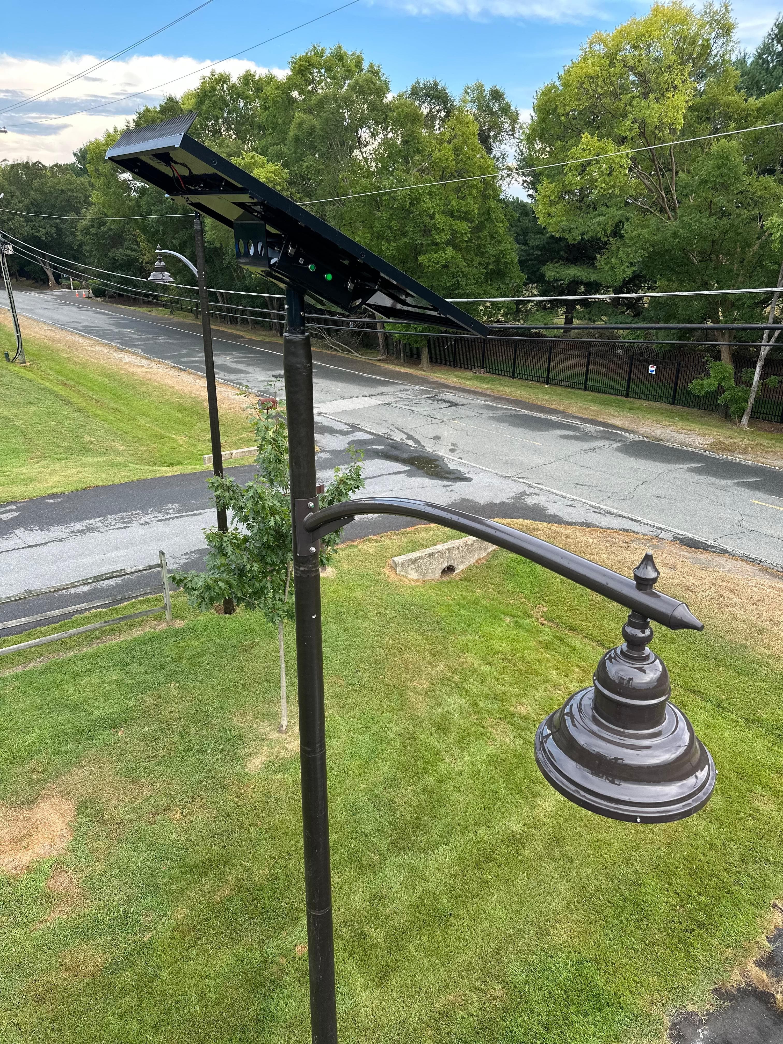Daytime detail of the All Seasons pole showing the solar panel and acorn-style light head