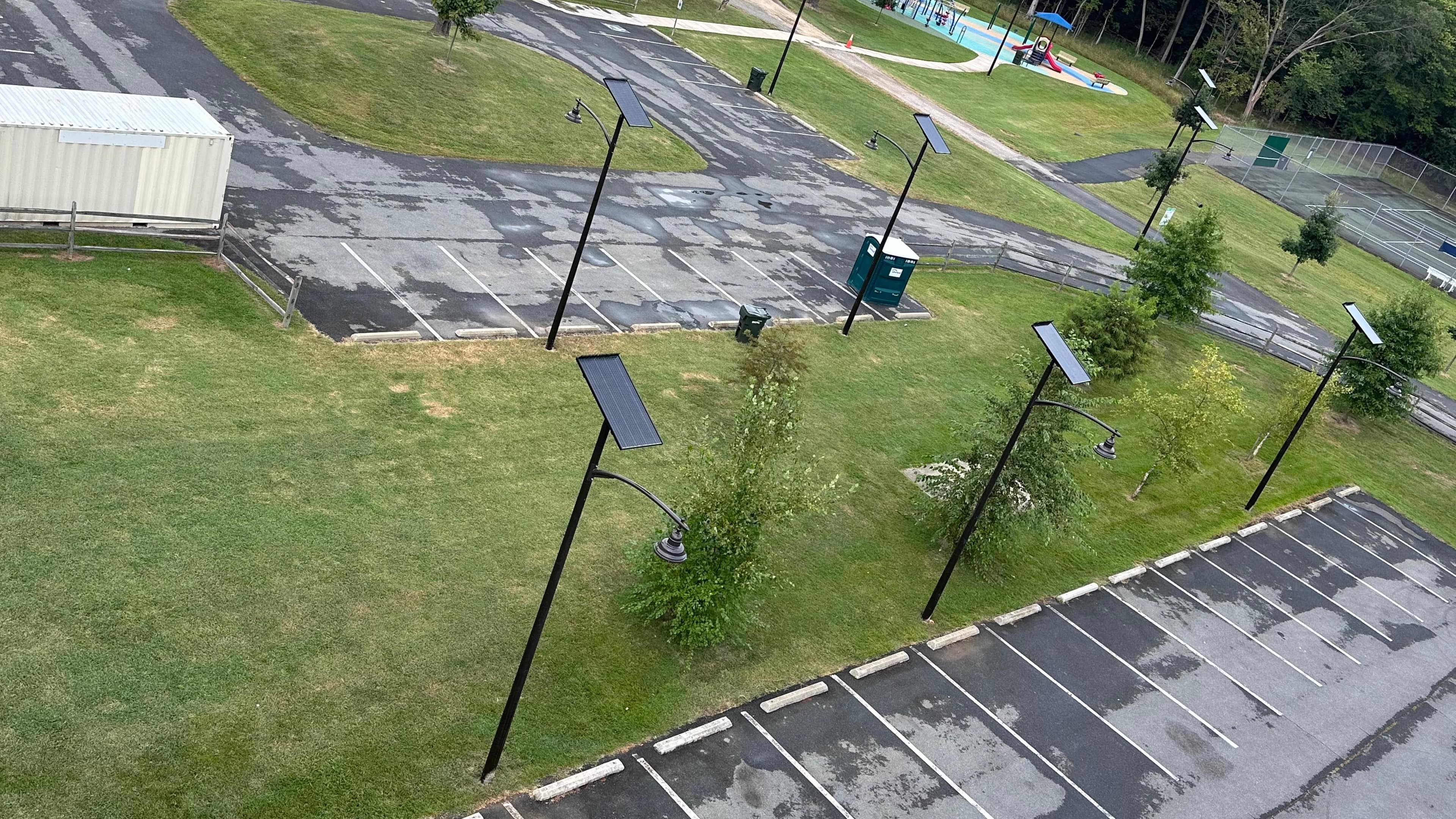 Aerial daytime view of multiple All Seasons poles arranged around the Riverview Park parking lot, with tennis courts and pool visible